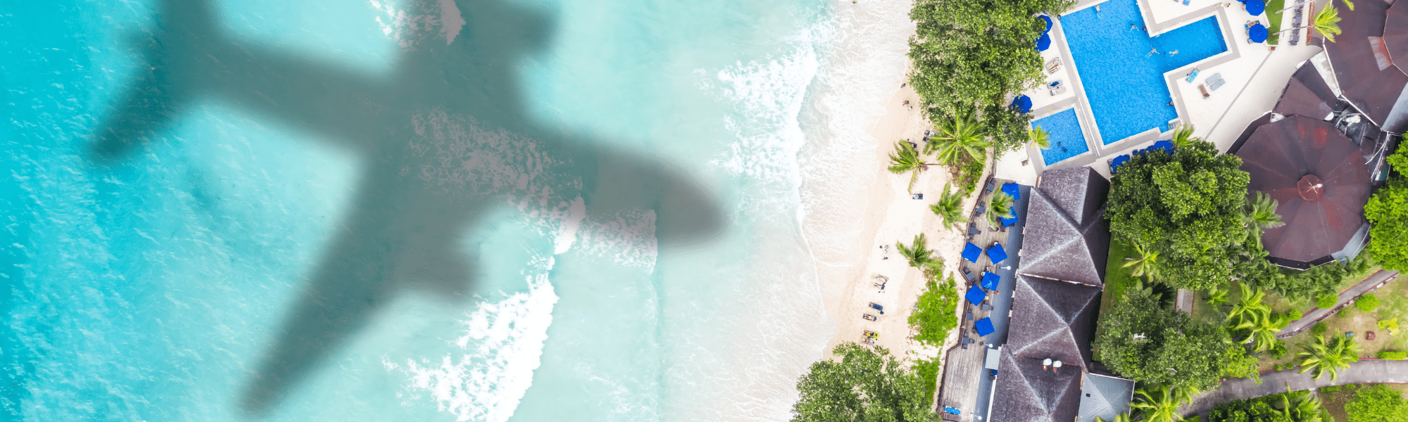 shadow of plane flying over water and beach by luxury resort