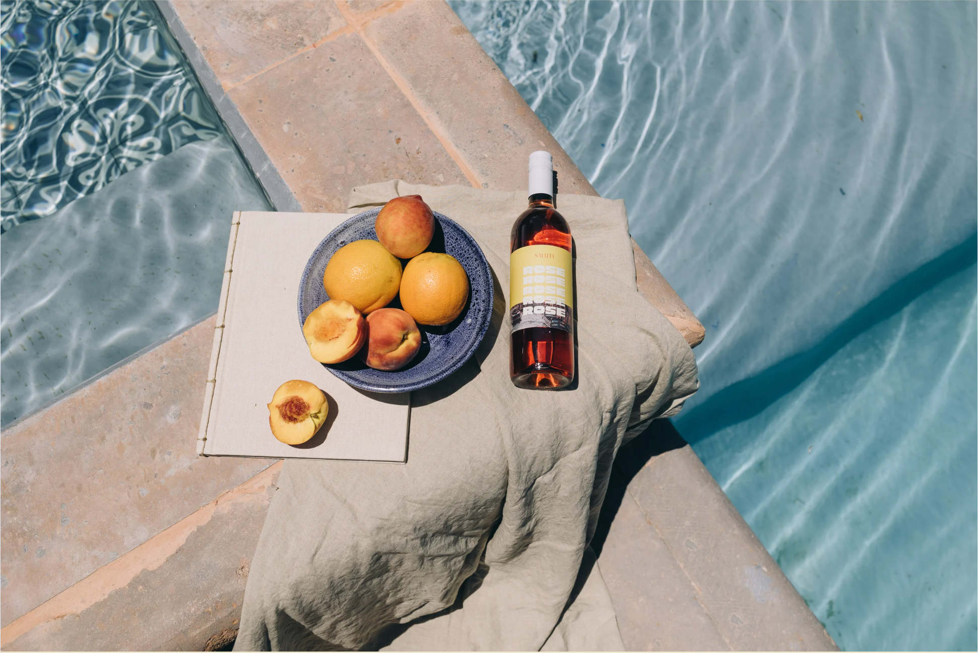 fresh fruit and bottle of wine on pool edge