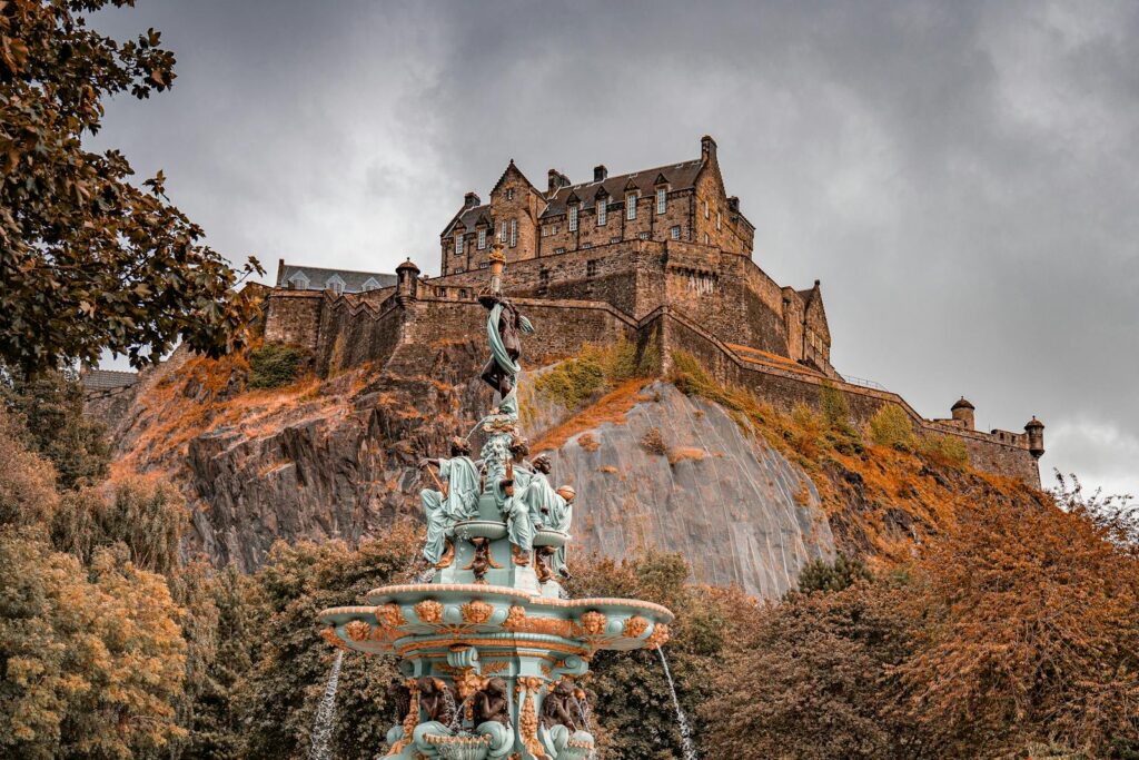 A majestic shot of Edinburgh Castle atop Castle Rock, surrounded by autumn foliage.