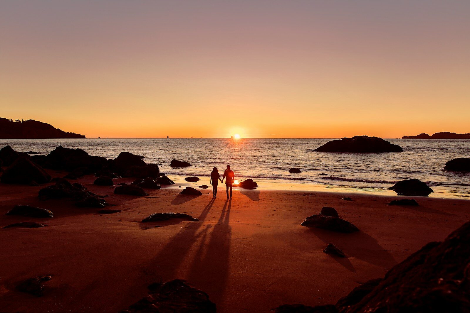 couple walking on beach during sunset