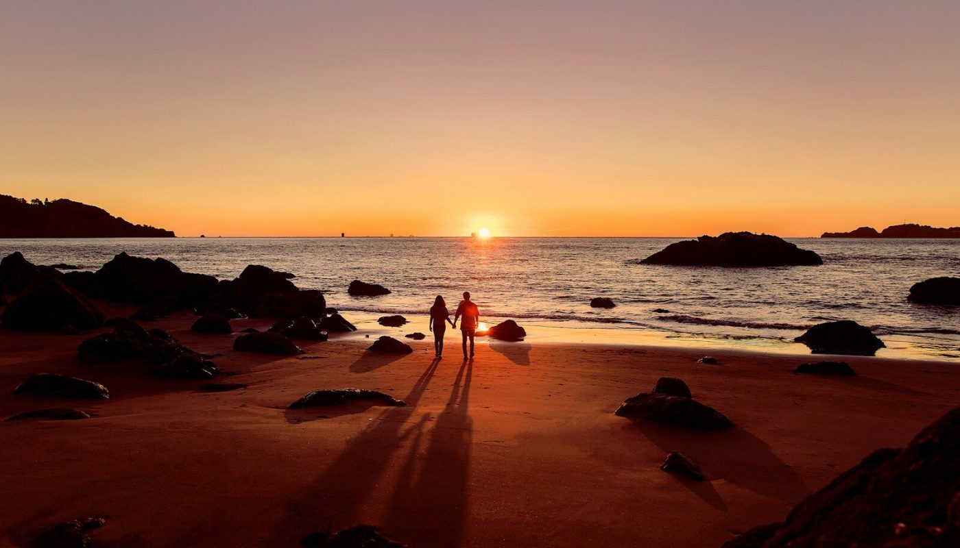 couple walking on beach during sunset